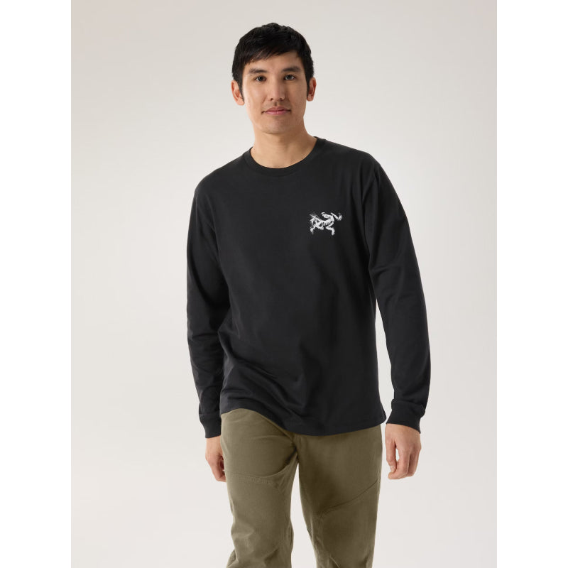 Person wearing a black long-sleeve shirt with a logo on a plain background Arc’teryx