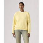 Person wearing a light yellow sweatshirt and light blue jeans on a plain background